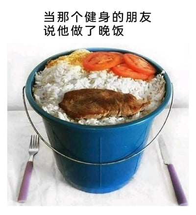 这是一张带有调侃性质的搞笑静态梗图，图片顶部配有文字“当那个健身的朋友说他做了晚饭”。画面主体是一个蓝色的塑料水桶，里面被米饭填满，米饭上放置着一块外形酷似老鼠的肉排，还有几片番茄和少量黄色的调料类物质，水桶的两侧摆放着刀叉，模拟正式用餐的场景。这张图通过夸张的容器选择和视觉上容易产生误解的“肉排”，来调侃健身人群为了补充蛋白质，饮食风格简单粗暴、看起来有些荒诞的特点，制造出强烈的反差搞笑效果。
