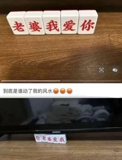 这是一张上下对比的原创拍摄图，上图展示了用五块麻将牌精心摆出的「老婆我爱你」字样，传递出向伴侣表达爱意的温馨意图；下图中原本的麻将牌被重新排列，变成了「你老婆爱我」，将温馨的告白瞬间转化为充满挑衅感的恶搞内容。图中间的配文「到底是谁动了我的风水😡😡😡」搭配愤怒的表情，生动表现出主人发现自己的心意被恶搞后，又气又无奈的情绪。整个图片通过文字顺序的简单改变，制造出强烈的反差笑点，属于日常家庭整活类的趣味内容，没有谐音梗或双关含义。