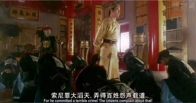 这是一张出自1992年香港古装喜剧电影《鹿鼎记》的影视截图，画面展现了充满中式古风的厅堂场景，红漆立柱、传统牌匾等元素营造出古代官署的氛围。画面中央高处，由周星驰饰演的韦小宝身着浅色古装，神态严肃，正义正言辞地对着下方的官员讲话；下方一众身着深色官服的官员全部低头跪拜，姿态恭敬。画面底部配有中英双语字幕，中文为“索尼罪大滔天，弄得百姓怨声载道”，英文对应翻译为“For he committed a terrible crime! The citizens complain about that!”，完整呈现了电影中韦小宝假借斥责索尼来推进自身目的的经典喜剧片段。