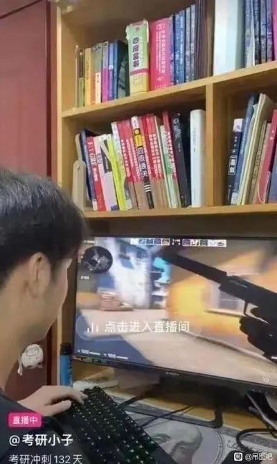 这张图呈现了极具反差感的一幕：画面中的用户标注为“考研小子”，左下角明确标注“考研冲刺132天”且处于直播状态，但他正专注地在电脑上玩射击类游戏，电脑屏幕上还显示着“点击进入直播间”的提示。画面上方的书架上摆满了各类考研复习用书，和他当下打游戏的行为形成强烈对比，讽刺了部分人表面营造出努力备考的假象，实际却在做与学习无关的事，充满了搞笑的反差感。