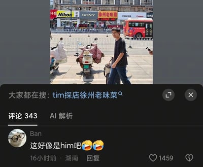 该图是社交媒体评论区截图，上半部分为城市街景：沿街商铺依次有尼康、索尼、徐州老味菜、富士、佳能的门店，路边停放着电动车，一名戴眼镜、穿黑色短袖T恤和蓝色牛仔裤的男子拉着行李箱走在人行道上，背景还可见红色公交车。图片下方显示平台搜索提示“大家都在搜：tim探店徐州老味菜”，下方展示一条获1459赞的热门评论，来自湖南用户Ban，发布于16小时前，内容为“这好像是him吧”并附带两个笑哭表情，该内容总评论数为343条。梗点在于该名路人的外形酷似沙盒游戏《我的世界》中的经典角色Him，结合关联的探店搜索热点引发网友调侃。