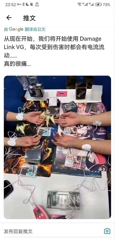 这是一张社交媒体截图，内容为一条推文。推文文本由Google翻译自日文，提到“从现在开始，我们将开始使用Damage Link VG，每次受到伤害时都会有电流流动……真的很痛…”。推文下方配有一张照片，显示几个人的手放在铺有卡牌的桌子上，手腕连接电极片和电线，周围散落着卡牌盒等设备，推测是在展示Damage Link VG产品，该产品可能在使用者“受伤”时通过电极释放电流导致痛苦体验。