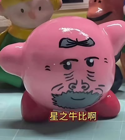 图片主体是一个粉色的星星形状摆件，被手绘上了滑稽的人脸五官，包括浓密的眉毛、带皱纹的眼睛、胡须和微笑的嘴巴。摆件前方有黄色文字"星之牛比啊"。背景中还有其他不同颜色和造型的玩偶。整体呈现出一种幽默搞笑的氛围。
