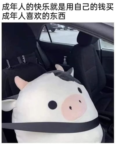 图片展示了汽车后座场景，一个大号呆萌奶牛造型毛绒玩具（带有粉色猪鼻特征）被安全带固定在座位上，显得十分可爱。顶部配有文字“成年人的快乐就是用自己的钱买成年人喜欢的东西”，通过可爱的毛绒玩具与文字结合，幽默又温馨地表达了成年人通过自主消费获得小确幸的生活态度。