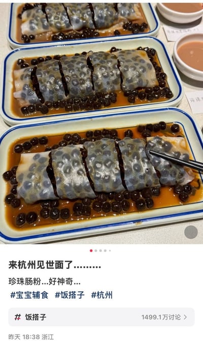 该内容为社交媒体发布的帖子截图，上半部分为实拍的三盘创意融合菜品珍珠肠粉：半透明的肠粉皮内包裹满了奶茶常用的黑珍珠，被切成段摆放在带蓝边的长方白盘中，盘底盛有棕色糖浆，盘边还搭配了两小碗蘸料，最下方的肠粉盘里有黑色筷子正夹起一段肠粉；下半部分为发布文案，内容为“来杭州见世面了……珍珠肠粉…好神奇…”，附带#宝宝辅食、#饭搭子、#杭州三个话题标签，还显示“饭搭子”话题共有1499.1万讨论量，帖子发布地点为浙江，发布时间为昨日18:38。