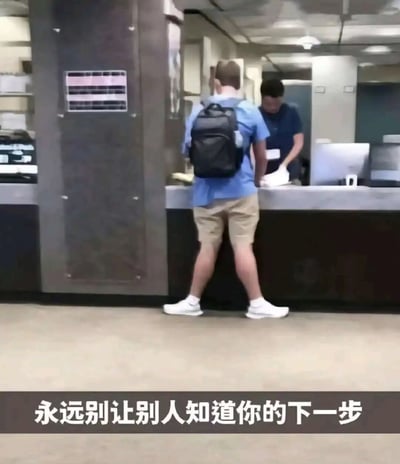 图片展示了一个办公室或服务场所的场景，一名背着黑色背包、穿着蓝色T恤和卡其色短裤的男子正站在服务台前，他的身体朝向柜台，但从背后视角看，他的姿势显得有些滑稽。图片底部配有文字“永远别让别人知道你的下一步”，形成一种幽默的反差效果。