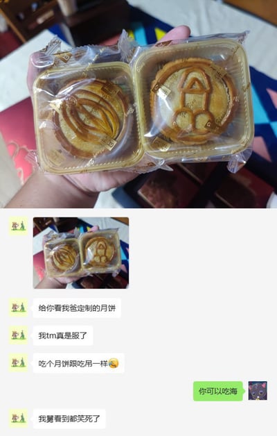 图片上半部分为一只手拿着两盒独立包装的月饼，左侧月饼表面有螺旋状花纹，右侧月饼表面的压花图案因形状特殊，神似一个人双手被绑、身体下垂的形象。下半部分是聊天记录截图，内容显示：发送者分享月饼照片后吐槽“我tm真是服了”“吃个月饼跟吃吊一样😂”，对方回复“你可以吃海”，发送者补充“我舅看到都笑死了”。整体通过月饼图案的视觉巧合引发幽默吐槽。