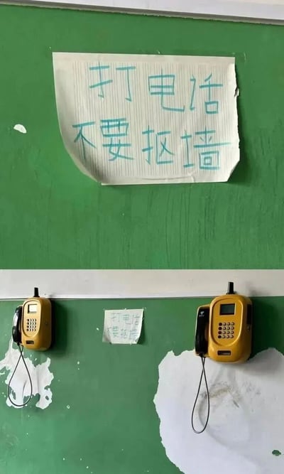 图片展示了绿色墙壁上的两部黄色壁挂电话，中间贴着一张手写纸条，上面写着‘打电话不要抠墙’。墙壁上有明显的油漆剥落痕迹，推测是人们打电话时习惯性抠墙导致的，纸条的提示带有幽默和温馨的意味。