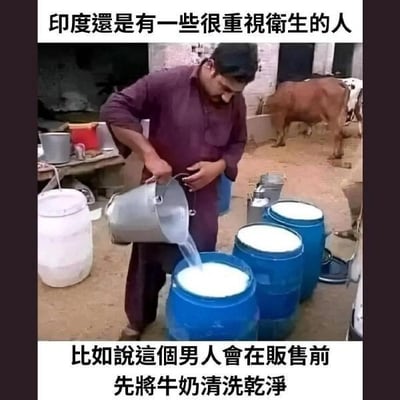 这是一张带有反讽文字的实拍梗图，画面中是一位身处印度户外简陋环境的男子，他正拿着金属容器往装满牛奶的蓝色桶里倒水，背景中可以看到一头牛和杂乱的作坊环境。图中的上下文字分别是“印度還是有一些很重視衛生的人”和“比如說這個男人會在販售前先將牛奶清洗乾淨”，这里运用了反讽的手法，实际男子是在往牛奶里兑水造假，并非“清洗牛奶”，用这种反差感来调侃印度的食品卫生状况，制造搞笑吐槽的效果。