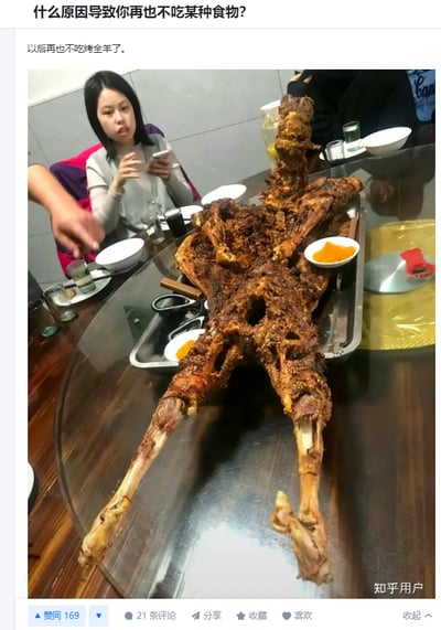 一张社交媒体截图，展示了一个人回答"什么原因导致你再也不吃某种食物?"的问题。图片中央是一整只烤全羊放在餐桌上，周围有几个人，其中一位女性正在看手机。回答内容是"以后再也不吃烤全羊了。"，暗示这顿烤全羊可能让人吃得太多或留下了不好的体验。
