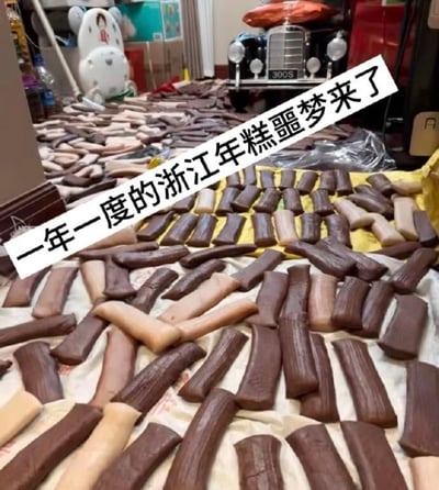 房间内大量棕褐色和米白色的年糕被整齐或随意地铺在布上，堆积如山，占据了大部分空间。背景中可见玩具车、复古汽车模型（300S）和纸箱等家庭物品，营造出生活化场景。图片上方有醒目的白色文字标注“一年一度的浙江年糕噩梦来了”，以幽默调侃的语气描述浙江地区新年期间制作或收到大量年糕的传统，因数量过多而被戏称为“噩梦”。