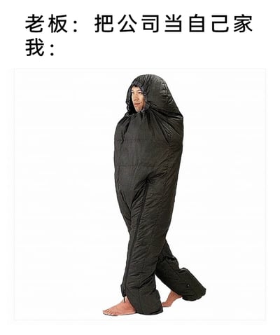 这是一张针对职场场景的吐槽类梗图，上方文字呈现老板对员工说的话术“把公司当自己家”，下方配图为一位真人穿着黑色的连体可穿戴睡袋，仅露出头部和双脚，面带微笑地行走，用夸张、戏谑的方式“践行”老板的要求，通过这种反差感，调侃老板的职场话术，同时表达员工希望在公司像在家一样放松休息的真实心态，精准戳中职场人的共鸣点，属于典型的职场吐槽内容。