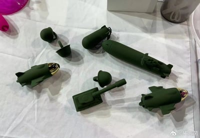 图片展示了一组绿色军事主题的玩具模型，包括导弹、坦克、飞机等造型，整齐摆放在白色布料上。模型整体为军绿色，部分细节如导弹头部、飞机前端有金色或红色装饰，造型小巧精致，充满趣味。