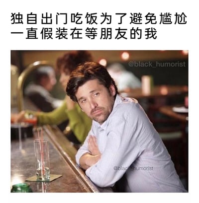 这是一张调侃社恐人群日常的搞笑梗图，上方配有文字“独自出门吃饭为了避免尴尬一直假装在等朋友的我”，图中是美剧《实习医生格蕾》里的角色德里克·谢泼德的剧照，他双臂交叉趴在吧台前，神情落寞局促，眼神带着无奈，吧台上只有一杯几乎喝完的饮品，完美还原了独自在外就餐时，为了不让自己显得孤单尴尬，刻意装作在等待朋友的社恐心态，引发很多有类似经历的人的共鸣。