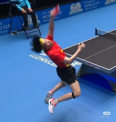 图片捕捉了2025年澳门ITTF男子世界杯乒乓球比赛中的精彩瞬间。一名中国乒乓球队员身着红色运动服，佩戴黄色头带，正处于高高跃起全力扣杀的动态姿态中。运动员身体后仰，右臂完全伸展，手中的红色球拍即将击中乒乓球，展现出极强的爆发力和竞技状态。背景中可以看到蓝色的比赛场地，场边有裁判坐在高脚椅上观赛，场地四周的广告牌上清晰显示着"ITTF MEN'S WORLD CUP MACAO 2025"的赛事信息，地面上还印有"LUZHOULAOJIA"的字样。整个画面充满动感与张力，完美呈现了乒乓球运动的速度与激情。