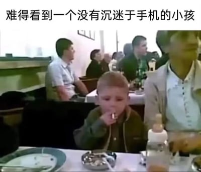 这是一张餐厅场景的实拍图，画面前景的小孩没有像当下多数孩童一样沉迷手机，而是做出抽烟的动作，将香烟叼在嘴边，面前的餐桌上同时摆放着奶瓶和烟灰缸，形成极具冲击的荒诞反差；图片上方配文“难得看到一个没有沉迷于手机的小孩”，用反讽的方式放大了这种反常场景的搞笑效果，背景中能看到餐厅内的其他顾客，整体氛围因小孩的反常行为显得格外怪异又充满调侃意味，讽刺了比起沉迷手机，小孩抽烟这种更离谱的行为带来的反差冲击。