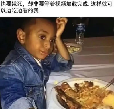 这张梗图展示了一个小孩坐在餐桌前，面前摆放着炸鸡和薯条等食物，他单手撑头，表情严肃地看着前方。图片上方配有文字：'快要饿死，却非要等着视频加载完成，这样就可以边吃边看的我：'，幽默地描绘了现代人宁愿忍受饥饿也要等视频加载完成以便边吃边看的生活习惯，反映了数字娱乐对日常生活的影响。