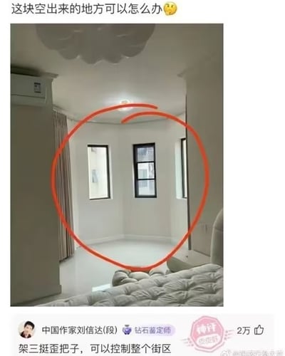 这张图是社交平台的内容截图，上方是用户发布的求助提问，配文“这块空出来的地方可以怎么办”并附带疑惑表情，下方配图是卧室的实拍场景，用红色圆圈标注出了房间内弧形墙面的拐角空地，该区域墙面开设了三扇窗户，暂时没有摆放任何家具。截图下方是平台用户“中国作家刘信达(段)”的高赞评论，内容为“架三挺歪把子，可以控制整个街区”，该评论带有“钻石鉴定师”的平台认证标识，获2万点赞，同时被标记为“神评”，右下角带有皮皮虾平台的水印。