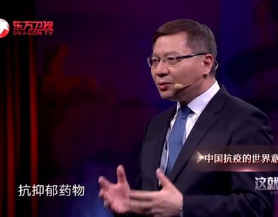图片显示一位戴着眼镜、穿着西装的男性正在东方卫视的节目中进行演讲。他戴着耳麦，双手张开，表情专注。背景为紫色调，左上角有东方卫视的标志。屏幕上有两行字幕，分别是“抗抑郁药物”和“中国抗疫的世界意...”。