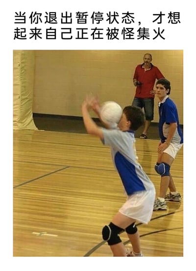 这是一张结合游戏场景的搞笑梗图，上方配文“当你退出暂停状态，才想起来自己正在被怪集火”，下方是室内排球场地的真实照片：一名穿着蓝灰拼接运动服的小男孩抬手准备接球，结果排球直接砸在他的脸上，他的动作定格在反应不及的瞬间；旁边的队友半蹲在地，露出惊讶的表情注视着他；后方还有一位穿红色上衣的成年人双手叉腰，面带微笑看着场上的情况。这张图用现实中运动失误的窘迫画面，精准类比了游戏玩家暂停游戏后回到对局，发现自己正处于怪物围攻中、来不及反应的尴尬处境，将游戏里的突发状况用真实搞笑场景具象化，让游戏玩家能产生强烈共鸣。