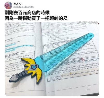 社交媒体用户@ebitenudon333分享了自己在百元商店冲动购买的一把造型独特的宝剑形状尺子。图片中，这把蓝色透明的尺子带有黄色翅膀装饰的剑柄，放置在一本打开的日文书籍上，尺子上有清晰的厘米刻度。上方文字描述了购买时的冲动心情，整体给人一种发现有趣小物的惊喜感。