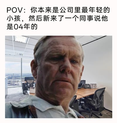 这是一张职场主题的搞笑meme，上方配文描述了场景：原本是公司里最年轻的人，在得知新同事是04年出生后，心态发生巨大变化。图中通过AI换脸将老年男性的沧桑沮丧的面容合成在现代化办公室场景中，用夸张的视觉效果，生动表现出原本“最小辈”的人在遇到更年轻的新同事后，瞬间产生的年龄焦虑和“变老”的搞笑心态，精准戳中职场年轻人关于年龄的趣味痛点，引发共鸣。