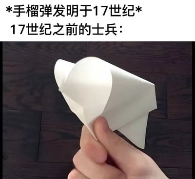 图片上半部分为文字说明：“*手榴弹发明于17世纪* 17世纪之前的士兵：”，下半部分是一只手握着一个白色纸飞机的特写照片，背景为深色木质地板。通过将纸飞机幽默地类比为手榴弹发明前士兵的“替代品”，形成历史与日常物品的趣味反差，达到搞笑效果。