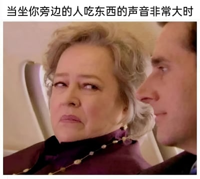 图片展示了一位头发花白的女性侧身看向邻座的场景，她眉头微皱，嘴角下撇，表情中透露出明显的烦躁和不满。图片上方配有文字“当坐你旁边的人吃东西的声音非常大时”，精准捕捉了人们在公共场合遇到噪音干扰时的无奈情绪，通过夸张的表情形成幽默效果。