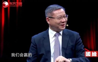 这是东方卫视某节目的视频截图，画面中的人物是张维为，他身着深色西装搭配白衬衫与紫色领带，戴着眼镜，面带微笑侧头看向画面右侧，左手握拳，画面下方配有白色文字“我们会赢的”，传递出一种自信、笃定的必胜态度。