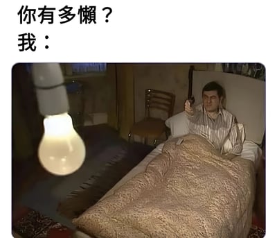 图片上方配有文字“你有多懒？我：”，下方是一张照片：一名男子躺在床上，盖着棕色毯子，穿着条纹睡衣，右手拿着遥控器指向悬挂在床头的亮着的灯泡。房间内还有一把椅子等简单家具。通过夸张的场景幽默展现“极度懒惰”——连开灯都懒得起身，要用遥控器操作。