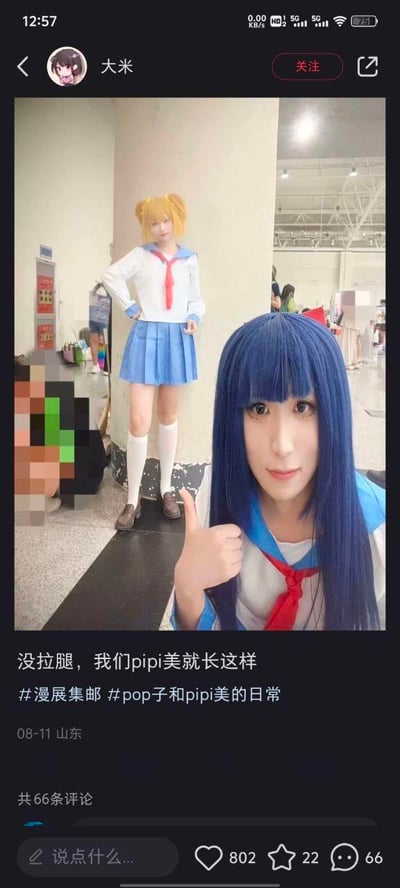 社交媒体截图中展示了两位漫展coser的合影。前景是蓝发coser（pipi美）正举着手机自拍，她留着齐刘海长直发，身穿蓝白水手服搭配红色领巾，右手竖起大拇指，表情自然。背景中站着金发双马尾coser（pop子），同样穿着同款水手服与蓝色百褶裙，双手叉腰，站姿挺拔。图片下方配文“没拉腿，我们pipi美就长这样”，幽默回应了可能存在的关于身材比例的疑问，体现了对原作角色形象的高度还原。