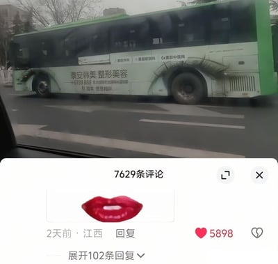该图为上下拼接的趣味内容，上半部分是乘车时拍摄的城市道路上行驶的绿白色公交车，车身印有“泰安韩美整形美容”的商业广告，标注了业务范围包含美容外科、美容皮肤科、美容中医科，还有联系电话、机构地址以及11周年感恩相伴的宣传语；巧合的是公交车后轮上方的深色污渍形状、位置和长睫毛高度相似，和医美广告的属性形成巧妙呼应。下半部分是社交媒体的评论区截图，显示共有7629条评论，其中一条仅发送红色嘴唇表情的评论发布于2天前、定位江西，获赞5898，还可展开102条回复。红唇表情和上半部分公交的“睫毛”污渍结合后恰好构成类似人脸的效果，形成充满巧合笑点的视觉梗。