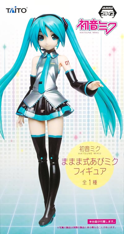 这是TAITO推出的ままま式初音未来景品手办的官方宣传图，展示了身着经典公式服的初音未来手办：标志性的湖蓝色双马尾长发，银灰亮面无袖上衣搭配同色系领带，黑色亮面短裙、长靴与臂套，左臂印有"01"标识，手办姿态自然舒展，完美还原初音未来的经典形象。图中附带日文产品说明，标注该手办仅有一种款式，且附带底座，同时提示宣传图与实物可能存在细微差异。