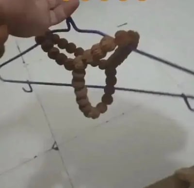 这张图片展示了一条用核桃串串成的丁字裤，被挂在铁丝衣架上。一只手正在展示这个创意组合。画面带有恶搞和幽默气息，将生活日常物品“核桃串”玩出了新花样。视觉反差强烈，是典型的网络脑洞发明恶搞。“丁字裤”造型和核桃的结合形成了令人忍俊不禁的独特梗点。此梗同时有一定双关和恶搞成分。