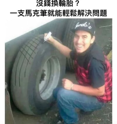 图片展示了一个幽默场景：一名男子正拿着马克笔在一个看起来磨损严重的轮胎上绘制胎纹。图片上方配有文字'没钱换轮胎？一支马克笔就能轻松解决问题'，以幽默的方式暗示用绘画胎纹来假装轮胎状况良好的搞笑'解决方案'。