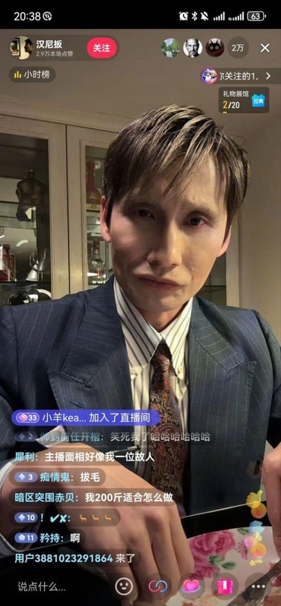 这是一张抖音平台的直播画面截图，主播账号为“汉尼扳”，本场点赞2.9万，在线人数约2万。主播身着深色条纹西装、竖条纹衬衫搭配花纹领带，通过妆容和神态刻意模仿电视剧《狂飙》中的角色高启强，造型和神态相似度较高，引发直播间观众的玩梗互动。画面下方的弹幕区里，观众留言五花八门，有的调侃“主播面相好像我一位故人”，有的发出爆笑的感叹，还有的询问“我200斤适合怎么做”，同时不断有新观众加入直播间，整体氛围轻松搞笑，充满趣味互动。界面还显示了抖音直播的常见元素，比如关注按钮、小时榜、礼物展馆入口，以及底部的评论、点赞、送礼等互动按钮。