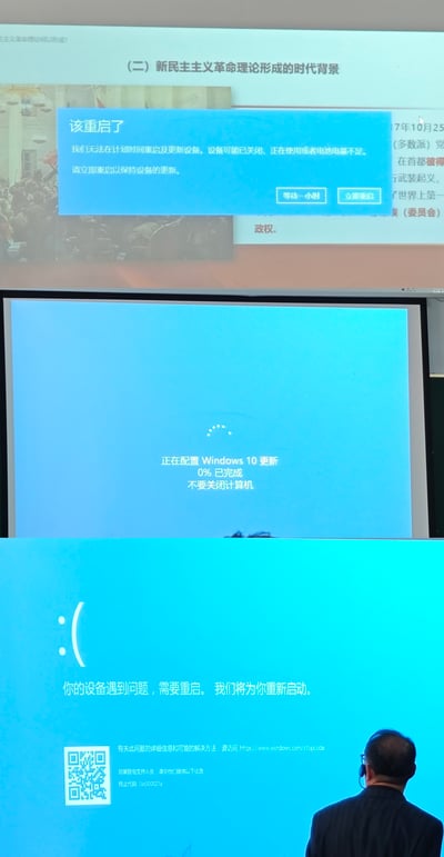 这张实拍图记录了学校课堂上的突发状况，画面从上至下依次呈现三个连续的界面内容：最上方是原本正在播放的主题为“新民主主义革命理论形成的时代背景”的教学PPT，界面被Windows系统弹出的蓝色更新提示弹窗遮挡，弹窗显示“该重启了”，说明无法在计划时间重启更新设备，提供“等待一小时”和“立即重启”两个操作选项；中间界面是执行操作后显示的Windows10更新配置页，显示“正在配置Windows 10 更新 0% 已完成 不要关闭计算机”的加载提示；最下方是更新配置失败后的系统蓝屏界面，提示“你的设备遇到问题，需要重启。我们将为你重新启动”，画面右下角有一位佩戴耳麦的男性教师背对镜头，正看向出现故障的显示屏幕，完整呈现了教学过程中因电脑系统强制更新失败打断正常授课的场景。