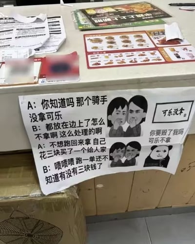 图片展示了餐馆柜台的真实场景，桌面上散落着菜单、单据和宣传页，核心是一张手写告示牌。牌上以A、B对话形式记录外卖骑手忘拿可乐的趣事：骑手因不想折返自掏3元购买，B调侃“跑一单还不知道有没有三块钱”。配图有两个捂嘴惊讶的卡通人物和熊猫头表情包，分别标注“可乐没拿”“你要毁了我吗”，整体风格幽默接地气，展现服务业日常的无奈与调侃。