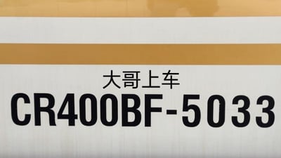 这是一张经过二次创作的图片，基础是复兴号CR400BF型动车组（编号5033）的车身实拍照片，该动车组因车身带有金色条纹，被铁路爱好者称为“金凤凰”。网友在车身编号的上方添加了“大哥上车”的口语化文字，用轻松幽默的语气来调侃，没有双关、谐音梗或暗示内容，整体氛围轻松搞笑，适合用来在和朋友约出行时作为趣味配图，或者铁路爱好者用来分享相关趣味内容。