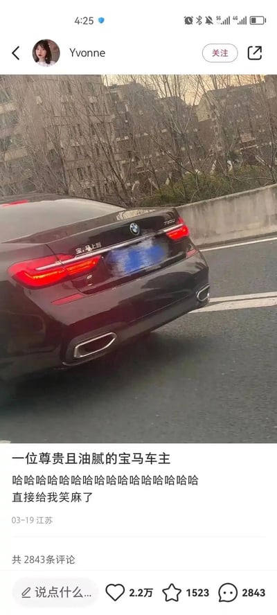 这是一张竖屏格式的社交媒体截图，内容为用户Yvonne在道路上拍摄的一辆黑色宝马730Li的车尾。车主将车辆原本的“宝马”标识创意改装为“宝，马上到”的字样，玩了谐音梗，十分诙谐有趣。发布者配文调侃“一位尊贵且油腻的宝马车主”，并附上一连串的笑声表达自己被逗笑的心情。该内容发布于2024年3月19日江苏地区，获得了2.2万次点赞、1523次收藏以及2843条评论，车牌部分做了马赛克打码处理，背景是城市道路旁的居民楼与树木。