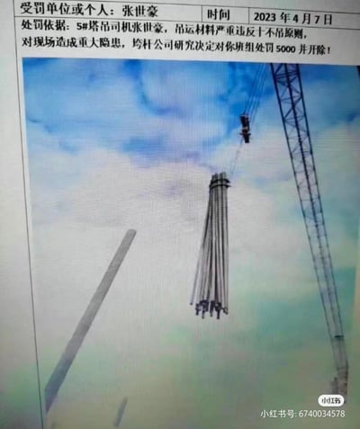 一张建筑施工安全违规的处罚通知单，上方是文字说明部分，下方配有一张塔吊吊运材料的现场图片。通知单显示塔吊司机张世豪因严重违反"十不吊"原则，对现场造成重大隐患，被垮杆公司处罚5000元并开除。图片中可以看到高耸的塔吊正在工作，背景是蓝天白云。