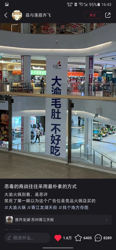 这是一张生活分享类社交媒体的截图，主体内容是苏州胥江龙湖天街商场内悬挂的一条特殊广告横幅，横幅上方印有“天街 Paradise Walk”标识，横幅核心大字为“大渝毛肚不好吃”。配文调侃“恶毒的商战往往采用最朴素的方式”，表示第一眼误以为是竞品火锅店购买的广告位来恶评大渝火锅，实际是大渝火锅的反向营销创意。该内容由用户“菇与落霞齐飞”发布，显示发布地点为“首开龙湖·苏州胥江天街”，内容获得1.6万点赞、6405次收藏、8289条评论，属于记录线下趣味场景的实拍内容。