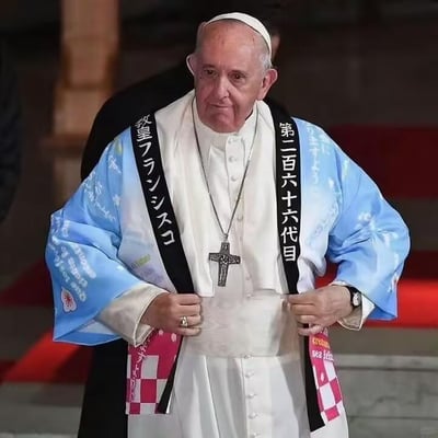图片中是教皇方济各的搞笑P图，他身穿原本的白色教袍，外面被P上了一件蓝色的日式和服，和服上有白色花纹装饰。胸前挂着十字架项链，腰间系着黑色绶带，上面用白色日文写着“教皇フランシスコ”和“第二百六十六代目”。教皇双手正整理着和服腰带，表情严肃，与身上滑稽的日式装扮形成鲜明对比，整体呈现出一种荒诞搞笑的效果。