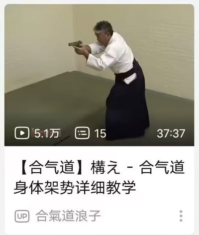 图片为一段合气道教学视频的截图，画面中一位身着白色上衣和深色裙裤（合气道服）的男性正专注演示身体架势，双手持类似训练工具向前伸出，背景是浅色墙壁和灰色地面。视频下方显示标题【合气道】構え - 合气道身体架势详细教学，以及播放数据：5.1万次观看、15条评论，视频时长37分37秒，UP主为“合氣道浪子”。