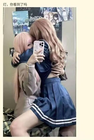 这是一张竖屏自拍照片，画面中两位身着二次元cos服装的女生正在镜子前亲密相拥：一位穿着蓝白配色的水手服，手持手机对着镜子自拍，脸部被手机和对方遮挡无法看清；另一位留着浅粉色长卷发，身着浅色系上衣，依偎在对方怀中，姿态亲昵温柔。图片上方配有文字「灯，你看到了吗」，背景墙面上贴有多张二次元动漫角色海报，整体氛围充满了二次元同好之间的温馨感，没有双关、谐音梗或暗示类内容。
