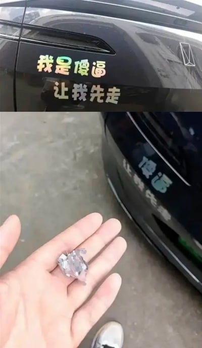 这是一张上下拼接的静态实拍图，上图展示了一辆黑色汽车的车身侧面，贴有镭射渐变效果的趣味贴纸，文字内容为“我是傻逼 让我先走”，这类贴纸通常是车主用以自嘲、希望其他车主避让的趣味标识；下图展示同辆车的车头部分，原本的车标已经被抠下碎裂，一只手正托着这块碎裂的车标，结合配文的反讽意味，笑点在于本想通过自嘲获得便利的车主，反而因为这一贴纸被他人抠走车标，形成了极具反差的搞笑效果。