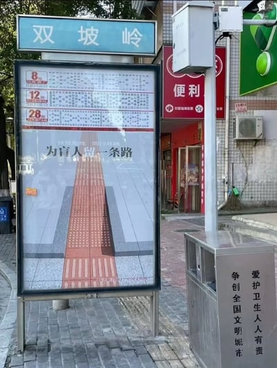 这张照片展示了城市街道上的一个公交站点场景。画面中央是一个公交站牌，顶部有蓝色的