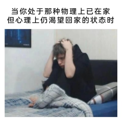 这是一张图文结合的情绪类表情包，上方配文“当你处于那种物理上已在家但心理上仍渴望回家的状态时”，下方画面是一位穿着黑色上衣的真人坐在床上，双手抓着头发，神情低落烦躁，腿上裹着毯子，整个人呈现出焦虑、无措的状态。这张图精准诠释了那种身体处于家中，但内心却没有归属感，依然渴望回到能让自己真正安心的“家”的复杂情绪，这种情绪可能源于对当前居住环境的疏离感、对过往熟悉居所的怀念，或是内心深处对“归属感”的强烈渴求。