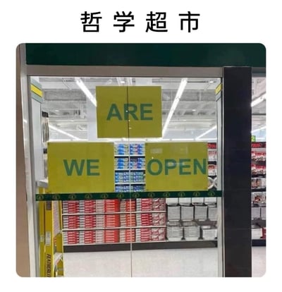 这是一张线下超市入口的实拍静态图，图上方标注有“哲学超市”字样。超市的玻璃推拉门上贴着三块黄色的标识牌，分别印有英文“WE”“ARE”“OPEN”，由于标识牌的位置分布，既可以组合成常规的营业标语“WE ARE OPEN（我们正在营业）”，也能被解读出充满哲学思辨感的疑问语气，仿佛在追问“我们是处于营业状态吗？”，这种文字排列的巧合制造出荒诞又有趣的效果，背景中可以看到超市货架上整齐摆放着各类商品。