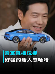 这张图是雷军直播时的画面截图，他面带笑容手持蓝色汽车模型，下方配文“雷军直播玩梗 好强的活人感哈哈”，玩的是2025年年度流行语“活人微死”的梗，用来调侃雷军在直播中表现得鲜活自然、没有模板化的生硬感，十分接地气，引发网友的趣味讨论。